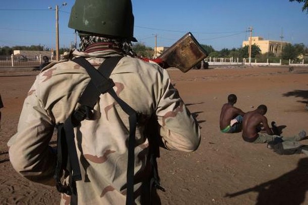 Un soldat malien surveille deux membres présumés du Mujao, le 22 février 2013 à Gao © AFP