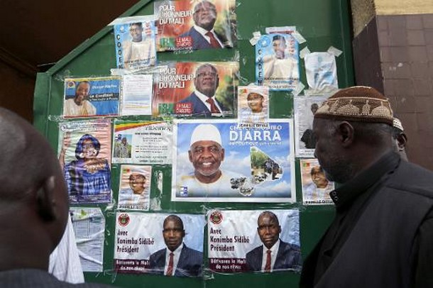 Des Maliens de France regardent, le 23 juillet 2013, des affiches électorales placardées à l'entrée du centre Bara à Montreuil, près de Paris © AFP