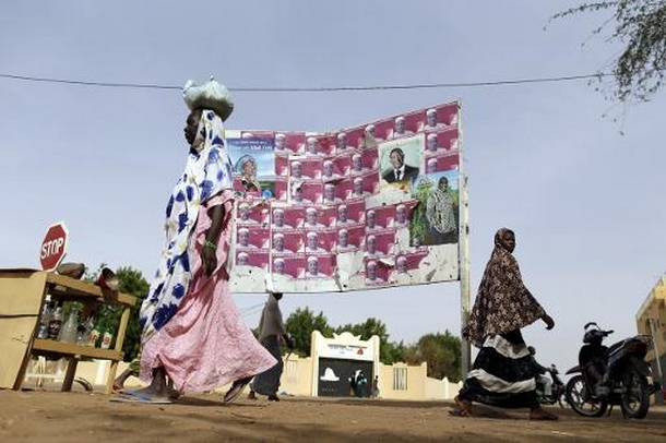 Des femmes passent devant des affiches électorales, le 25 juillet à Gao  © AFP