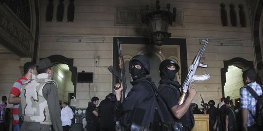 Des policiers montent la garde dans une salle de la mosquée où ont eu lieu des échanges de tirs entre forces de l'ordre et partisans de Mohamed Morsi, samedi. | REUTERS