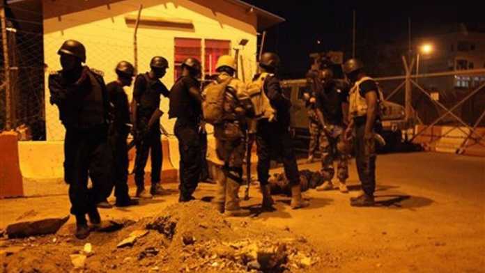 Soldiers stand next to the body of a suspected militant outside the European Union military missions entrance in Bamako, Mali, Monday, March 21, 2016. Extremists launched an attack Monday evening on the European Union military missions headquarters in the Malian capital, underscoring their determination to continue striking against Western interests in the region.(AP Photo/Baba Ahmed)