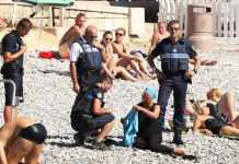 Une femme vêtue d’une tunique et d’un turban bleu est contrôlée et se voit infliger une amende sur la plage de la promenade des Anglais, à Nice, le 23 août. BESTIMAGE