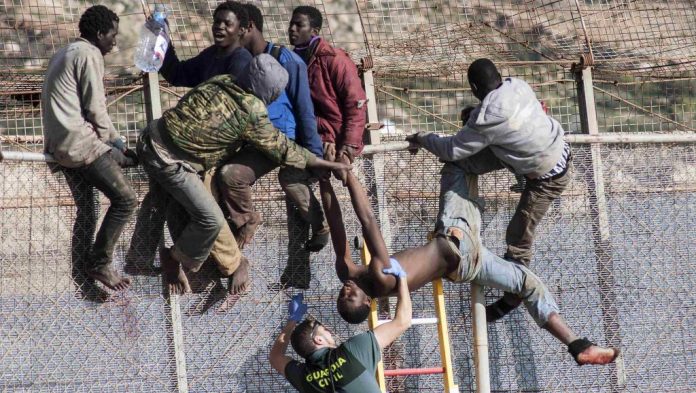 Les gardes civils espagnols tentent de déloger des migrants assis sur le grillage, frontière entre le Maroc et l’enclave de Ceuta