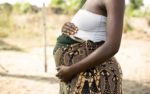 A pregnant African woman holding her stomach.