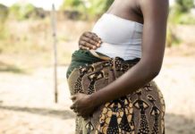 A pregnant African woman holding her stomach.